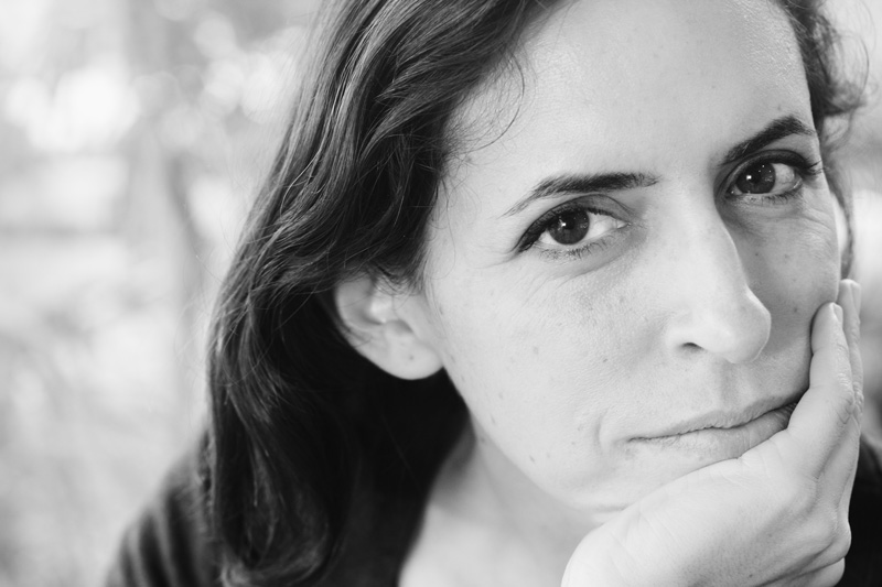 Photo en noir et blanc de Roxane de face, souriante, avec une main devant la bouche